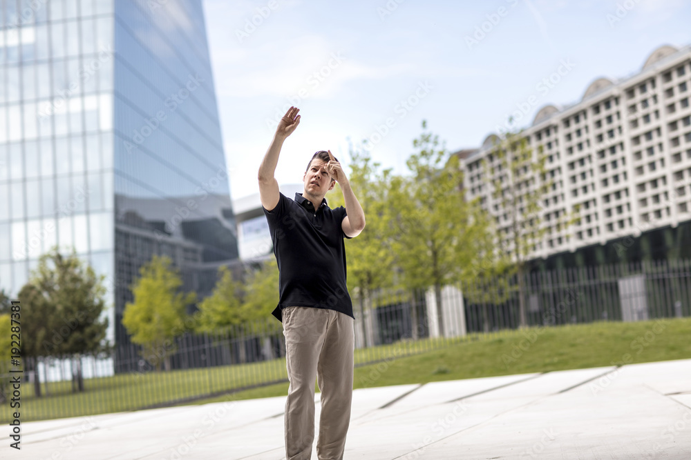 Man Making Hand Gestures in Front of Glass Building