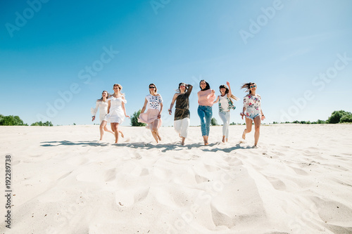 Beautiful stylish happy sexy slim young girls running on sand beach. Hands decorated buttonhole Party in Style boho. Maiden evening Hen-parties. Bachelorette. Close up