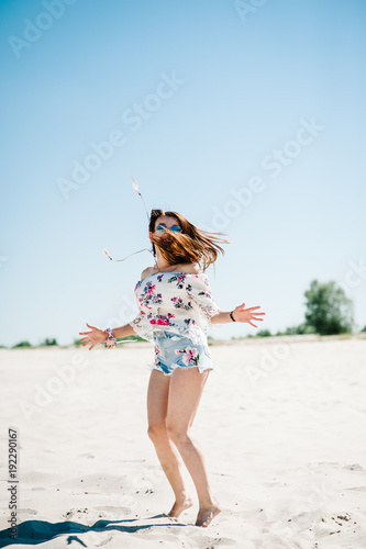 Beautiful stylish sexy young girl on sand, beach in the nature. Style boho. Jumps on the sand.