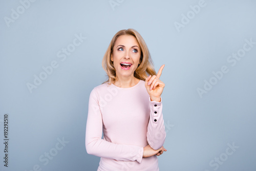 Portrait of pretty, charming, glad woman finding an idea, resolution, showing index finger with open mouth, isolated on grey background