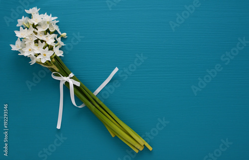 Fototapeta Naklejka Na Ścianę i Meble -  White narcissi, tied with ribbon on a blue background