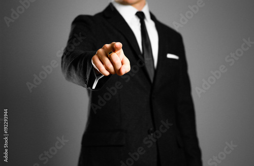 Businessman in a black suit, white shirt and tie pointing the finger at you. Studio shooting