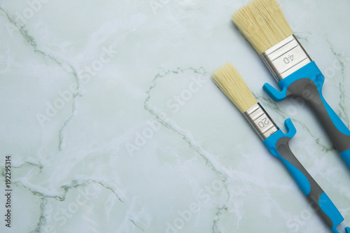 Painting the house. Two blue paint used brushes on white background with copy space, top view, flat lay