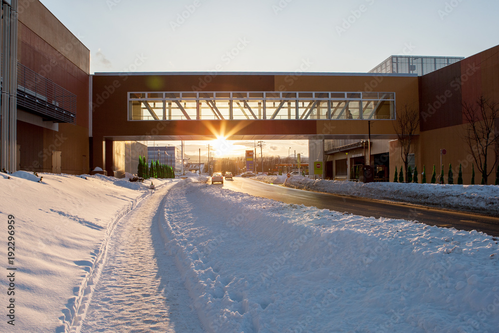 Winter road in snowy city landscape in sunset time in Sapporo, Hokkaido province, Japan for background.