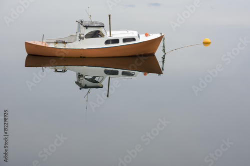 yellow boat reflected on a fjord in Ringstad at Lofoten Island in Norway photo