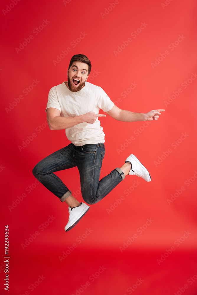 Emotional bearded man jumping pointing to copyspace. Emotional bearded man jumping pointing to copyspace.