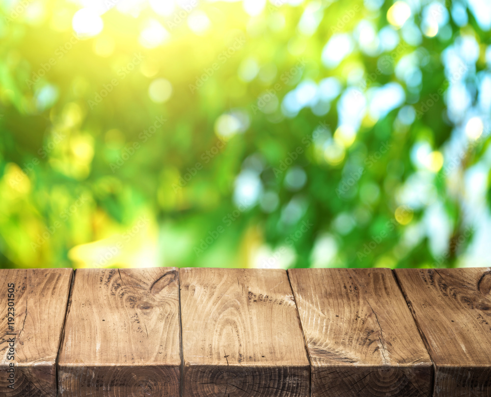 Old wooden table top and green foliage at the background. Old wooden table top and green foliage at the background.