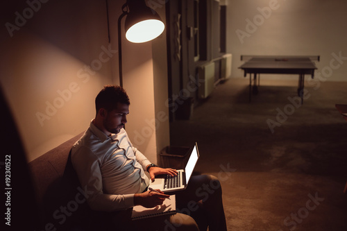Businessman working on laptop late at night in his office.
