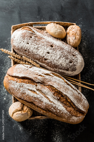 Vászonkép Bakery - rustic crusty loaves of bread and buns on black