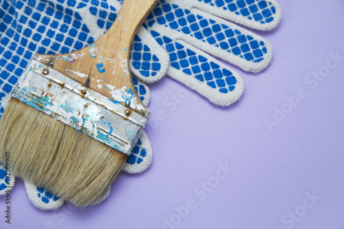 Painting the house. A wooden paint brush and protective gloves on blue background with copy space, top view, flat lay photo