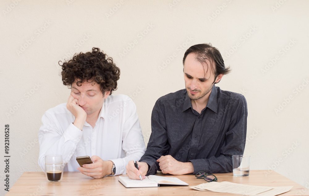 Young Caucasian businessman making a face at his colleague in office with light background. Young Caucasian businessman making a face at his colleague in office with light background.