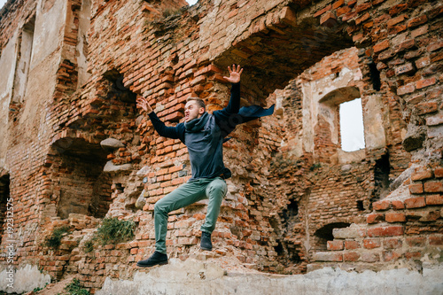 Adult crazy angry unusual excited male portrait. Businessman in flight motion. Young boy with funny comic expressive odd face emotions jumping from brick wall. Flying person. Sport activity outdoor. © benevolente