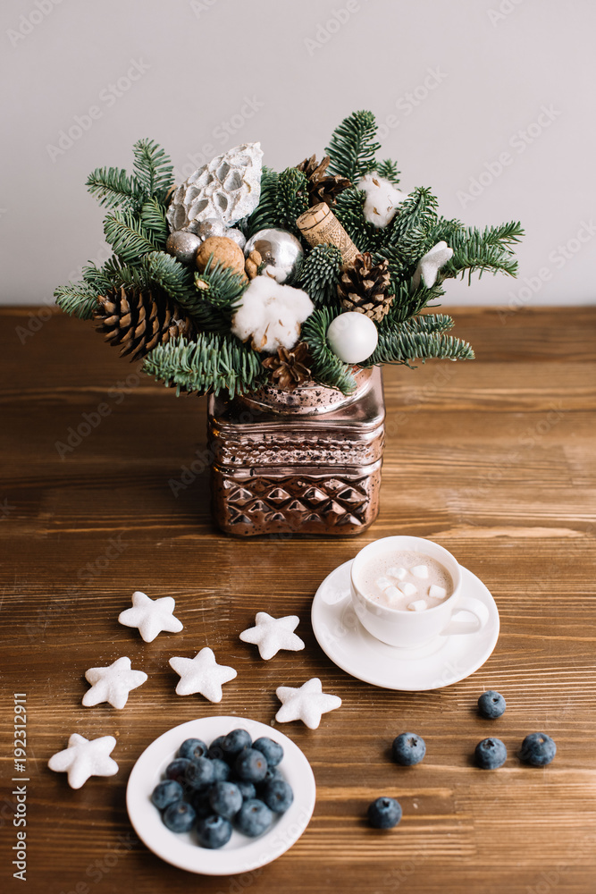 Delicious and healthy fresh blueberries with a cup of hot chocolate topped with marshmallow on the wooden table background, winter flower bouquet in a vase Delicious and healthy fresh blueberries with a cup of hot chocolate topped with marshmallow on the wooden table background, winter flower bouquet in a vase