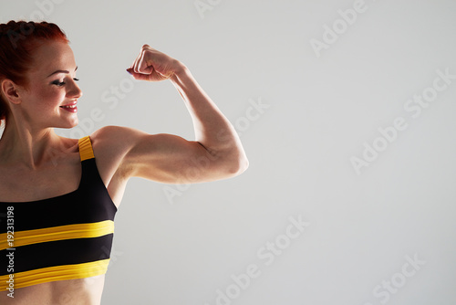cropped shot of smiley woman showing her biceps