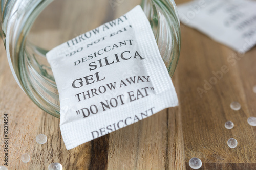 Desiccant or silica gel in a bottle and spread on the wooden background.