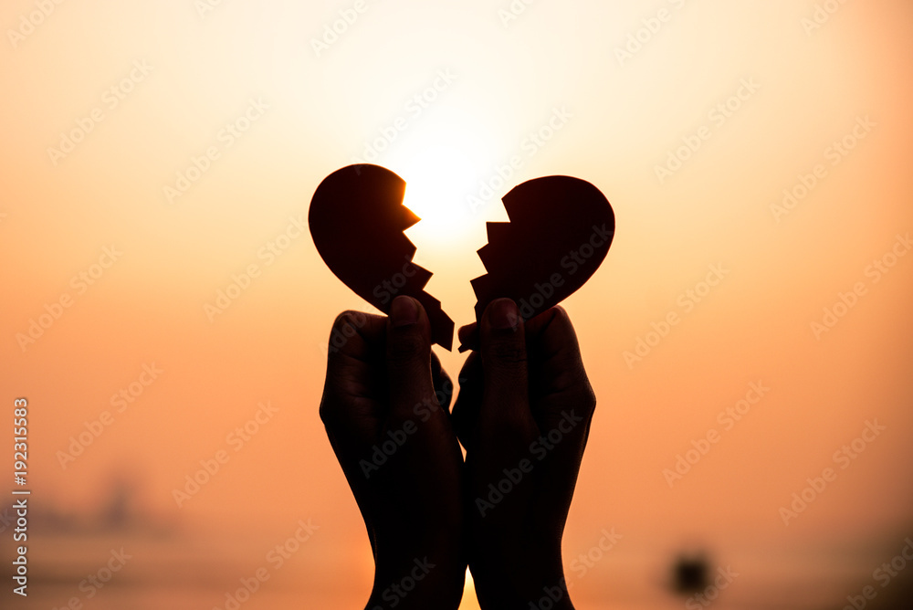 Close up and Silhouette of Woman hand holding broken paper red heart on sunset. Love, Wedding and Valentines day concept.