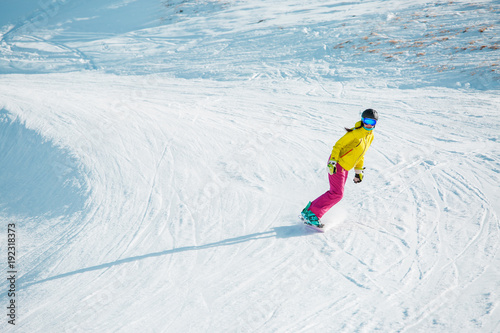 Photo of sports woman snowboarding from mountain slope