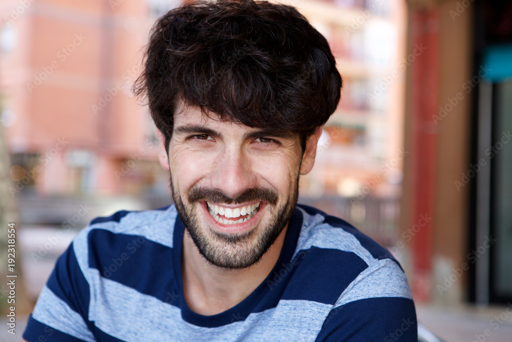 Close up handsome young man with beard laughing outside Close up handsome young man with beard laughing outside