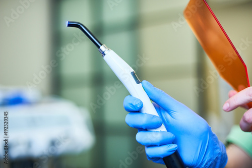 Tapet Hand in medical glove holding Dental UV curing light