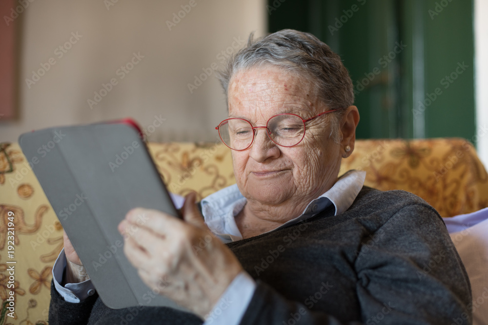 Elderly woman using tablet e-book selective focus on face portrait