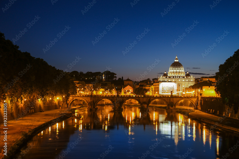 Night view of St. Peter's Basilica. Ponte Sant Angelo and Tiber River in Rome - Italy. Dramatic sunset with sbeautiful water reflection. Italy postcard