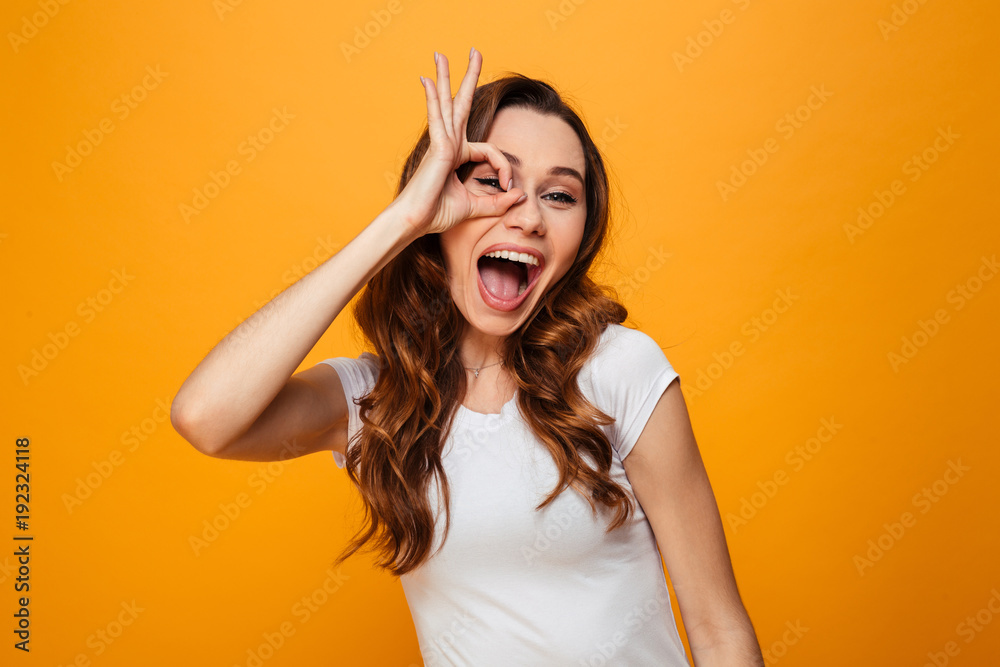 Cheerful brunette woman in t-shirt showing ok sign Cheerful brunette woman in t-shirt showing ok sign