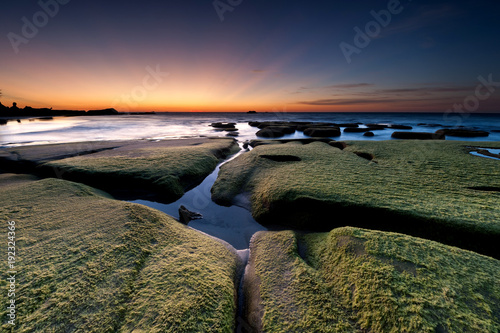 Sunset seascape at Tindakon Dazang Beach, Sabah Malaysia. Blue hour scene with natural coastal rocks and green moss. photo