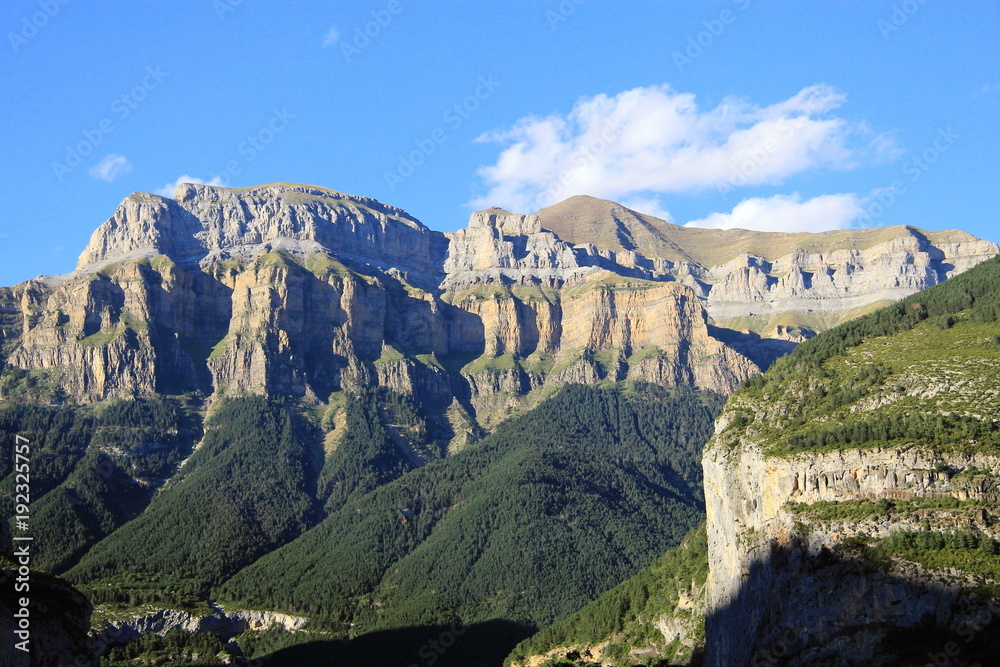 Valley of the Pyrenees. High mountains, blue sky, white clouds show a beautiful landscape at sunset.