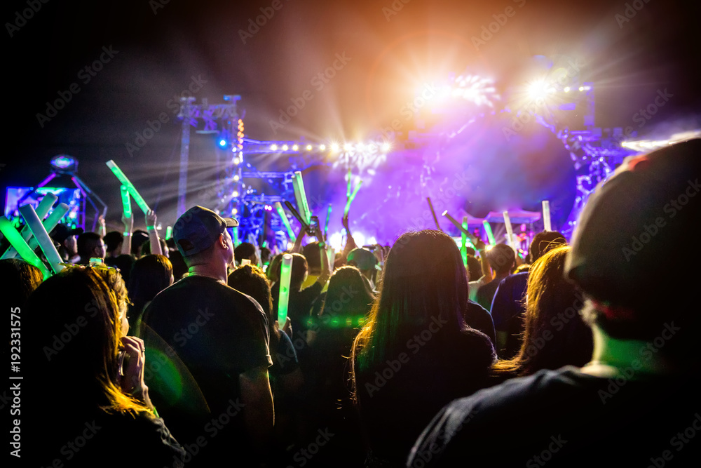 Many people are in local concert and all they standing in front of the stage. The audience in silhouette photo style. Many people are in the music festival event. 