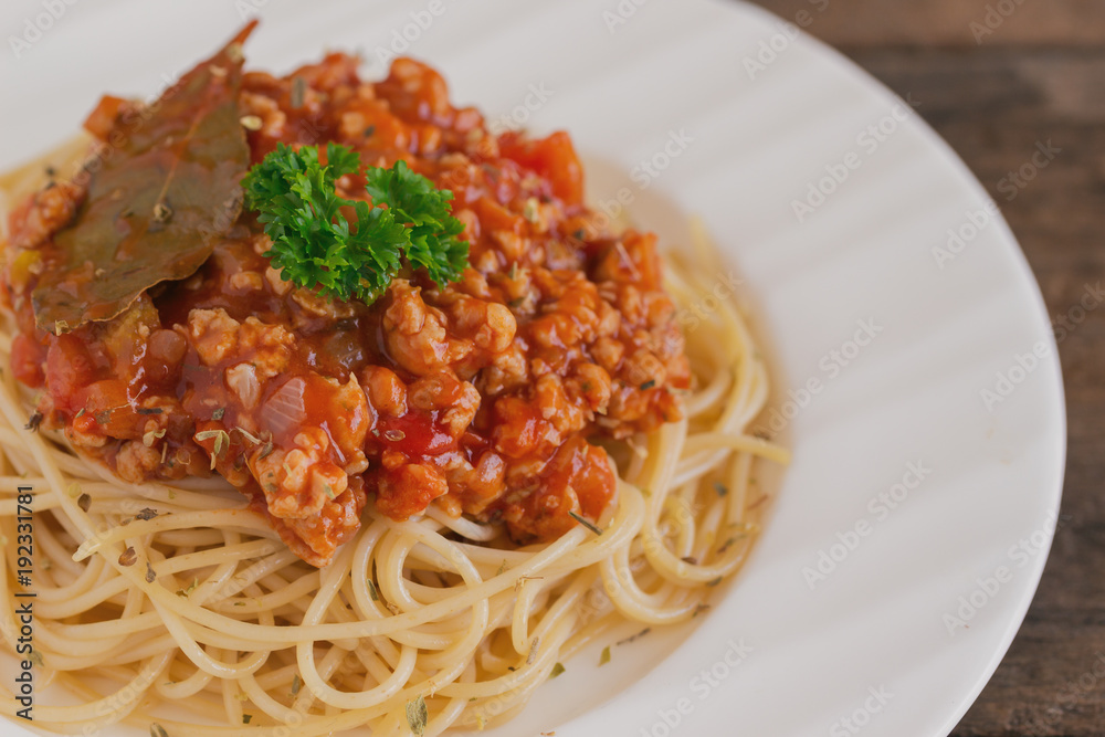 Spaghetti bolognese sauce with beef or pork,cheese,tomatoes and spices on white plate on wood table, top view with close up. Homemade delicious Italian traditional food for lunch or dinner. Spaghetti bolognese sauce with beef or pork,cheese,tomatoes and spices on white plate on wood table, top view with close up. Homemade delicious Italian traditional food for lunch or dinner.