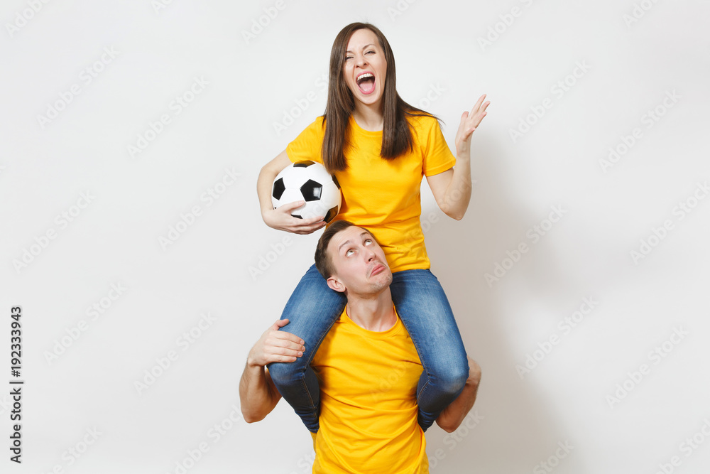 Inspired young couple, woman sit on man shoulders, fans with soccer ball cheering favorite football team expressive gesticulating hands isolated on white background. Family leisure, lifestyle concept. Inspired young couple, woman sit on man shoulders, fans with soccer ball cheering favorite football team expressive gesticulating hands isolated on white background. Family leisure, lifestyle concept.