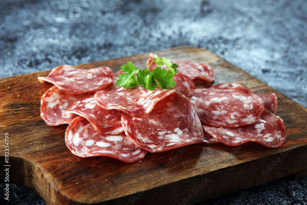 thinly sliced salami on a wooden texture on the background.