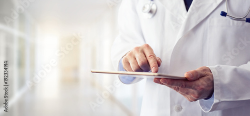 Slika na platnu Male doctor using his digital tablet in the hospital