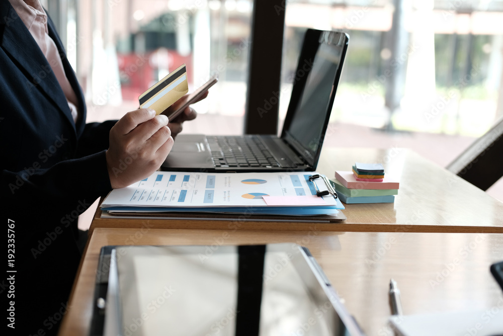 woman holding a credit card and using smart phone for online shopping at cafe. businesswoman purchase goods from internet at office. female adult make payment on bank website at workplace woman holding a credit card and using smart phone for online shopping at cafe. businesswoman purchase goods from internet at office. female adult make payment on bank website at workplace