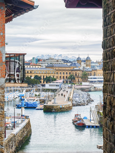 San Sebastian (Donostia) cityscape in cloudy winter day with the snowy mountains on horizon.