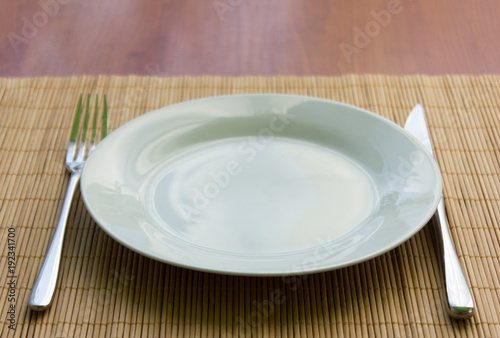white empty plate  fork and knife on the table