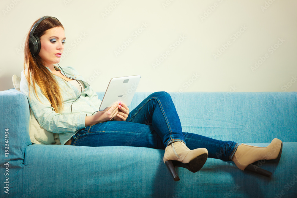 Woman with tablet headphones sitting on couch Woman with tablet headphones sitting on couch