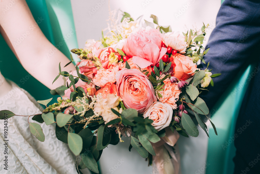 Bride and groom holding a wedding bouquet of beautiful roses Bride and groom holding a wedding bouquet of beautiful roses