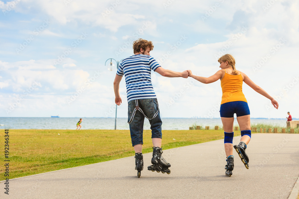 Obraz premium Young couple on roller skates riding outdoors