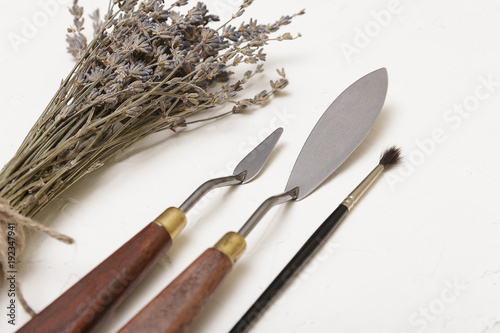 Sprigs of dry lavender and palette kneads lie diagonally on a white background