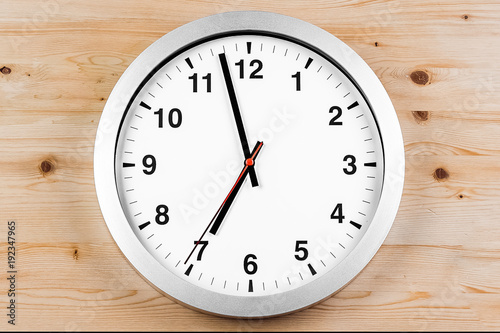 it's seven o'clock already, time to wake up for breakfast, modern white metallic alarm clock on wood background