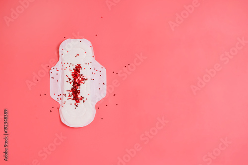 White sanitary pad with red sparkling glitter on it, woman health or body positive concept. Pink background. Copyspace photo