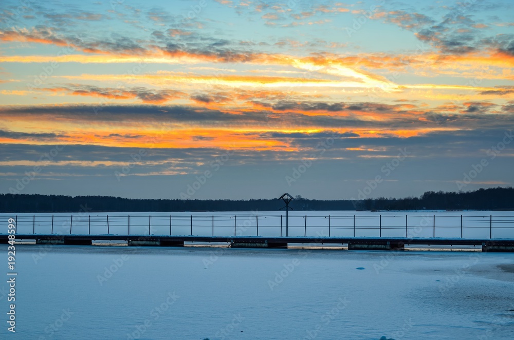 Fototapeta premium Afternoon winter landscape. A pier over a beautiful frozen lake.