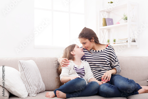Mother with her cute little daughter sitting on the sofa. photo