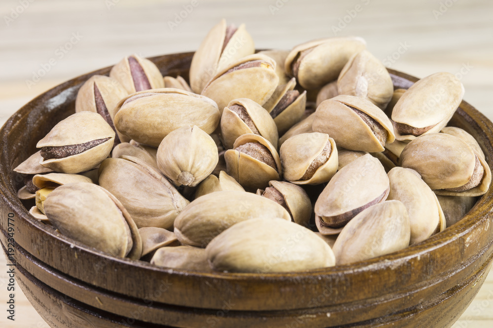 wooden bowl of pistachios on wooden background 