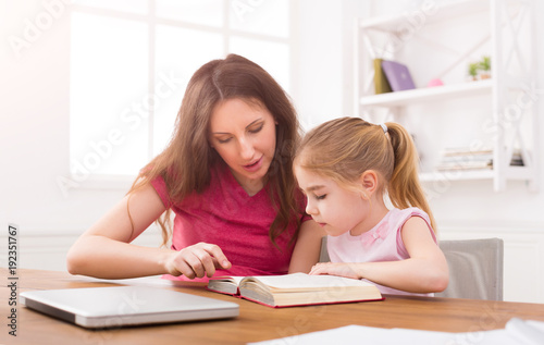 Mother helping her daughter with homework.