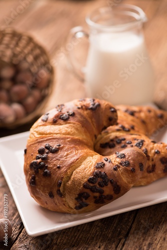 Fresh croissant on a wooden board  with milk. Freshly baked croissant on a dark wooden table.