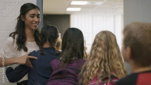 Enthusiastic teacher greeting students entering doorway to classroom / Provo, Utah, United States