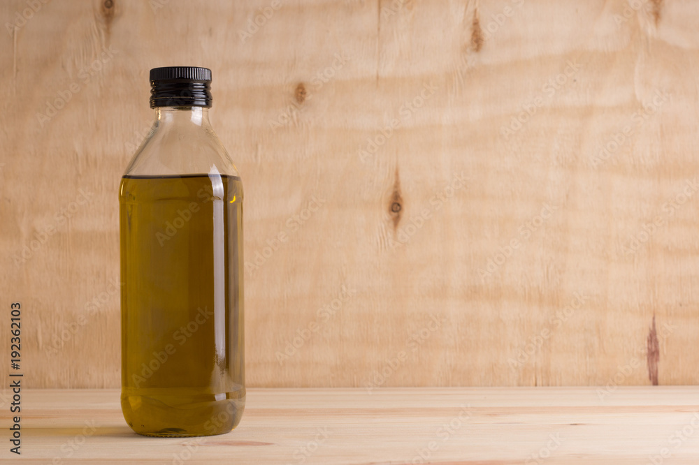 Olive oil in glass bottle on wooden background Olive oil in glass bottle on wooden background