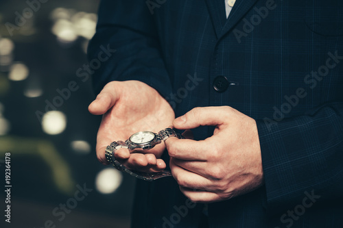 Business man in a suit shows his wristwatch.